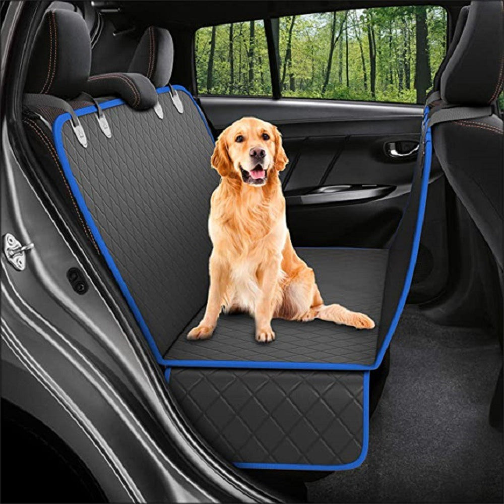 Dog sitting on a car seat cover in a vehicle with a forest view outside.