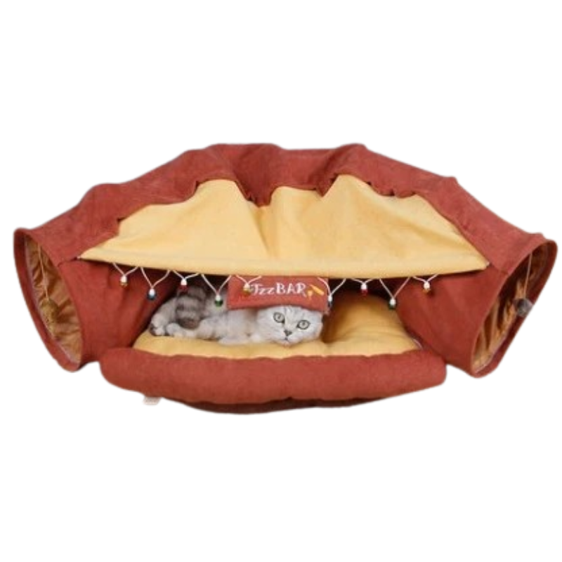 A cat tunnel pet bed shaped like a hot dog, with a gray cat lying inside. The exterior is reddish-brown, and the interior is a warm yellow.