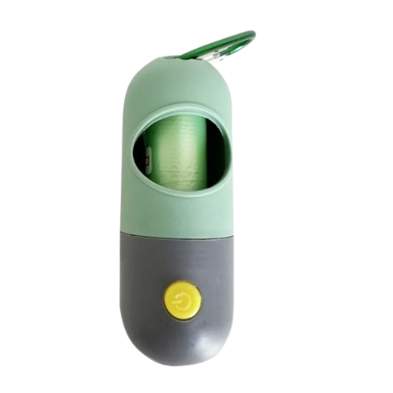 A capsule-shaped portable poop bag holder in sage green and dark gray, with a yellow button on the front and a green carabiner clip at the top, shown on a white background.