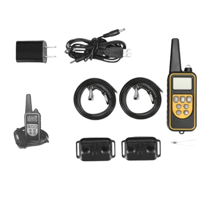 Dog training collar kit laid out on a white background, including a handheld transmitter with a yellow and black face, two black collars, two black receiver pads, a USB charging cable, a wall charger, an instruction booklet, and small accessories.