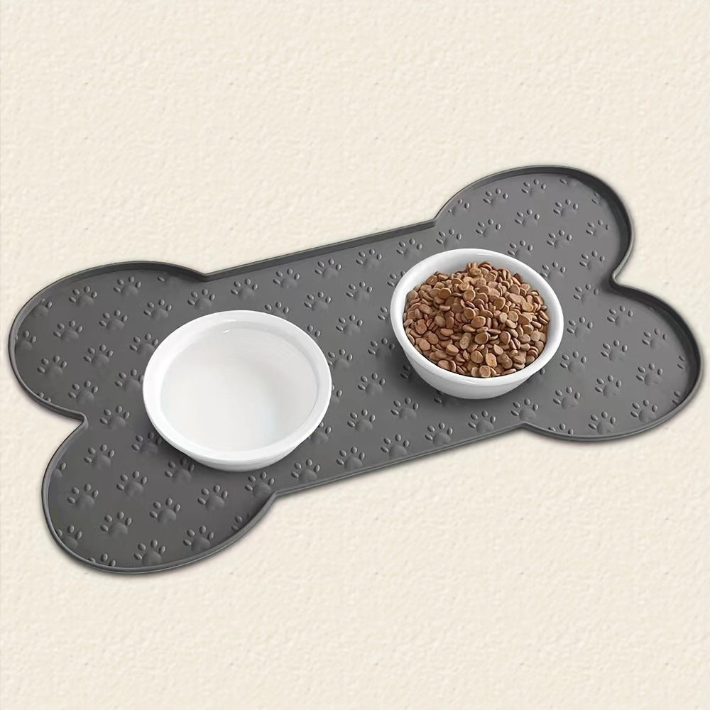 Gray bone-shaped pet mat with two white bowls on a beige background